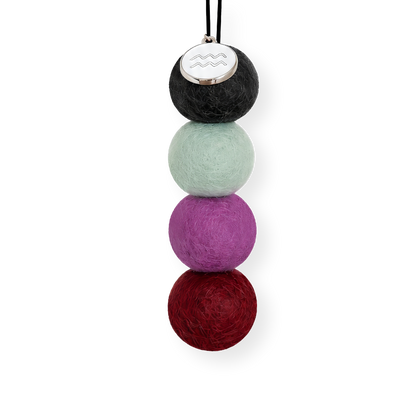 Four reusable wool felt air freshener balls in charcoal black, pale sage mint, vibrant bright purple and rich crimson red for the Aquarius Zodiac Set.