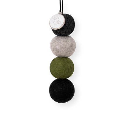 Four reusable wool felt air freshener balls in dark charcoal grey, cool stone grey, deep olive green, and classic black for the Capricorn Zodiac Set.