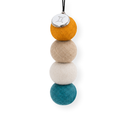 Four reusable wool felt air freshener balls in warm mustard yellow, sandy beige, soft cream, and vibrant teal blue for the Gemini Zodiac Set.