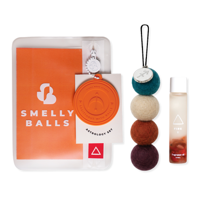 An astrology-themed 'Smelly Balls' kit by Smelly Balls, featuring an orange booklet, a wax seal keychain, a four-colored Reusable Air Freshener, and a 10ml fragrance oil bottle infused with crustals. 