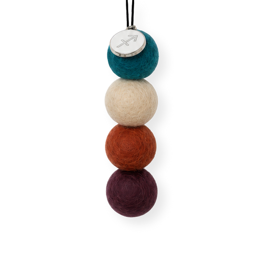 Four reusable wool felt air freshener balls in deep ocean teal blue, soft sandy beige, rust orange, and rich plum purple for the Sagittarius Zodiac Set.
