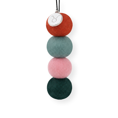 Taurus Zodiac Smelly Balls four reusable wool felt scent balls in an earthy palette of terracotta orange, sage green, soft blush pink, and deep forest green, strung on an elastic cord.